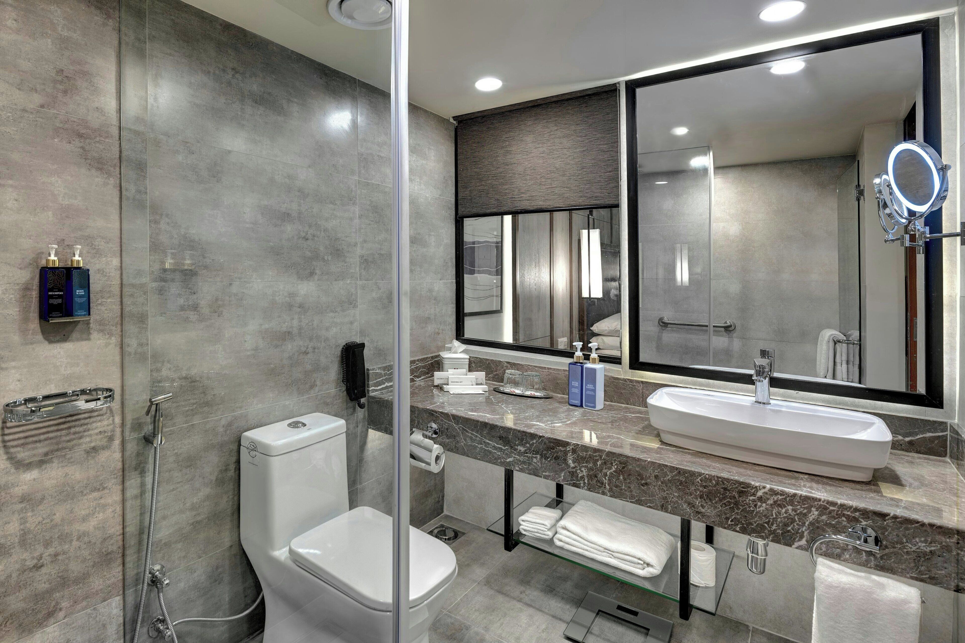 A modern bathroom with a toilet, bidet, and a large mirror with a built-in light.