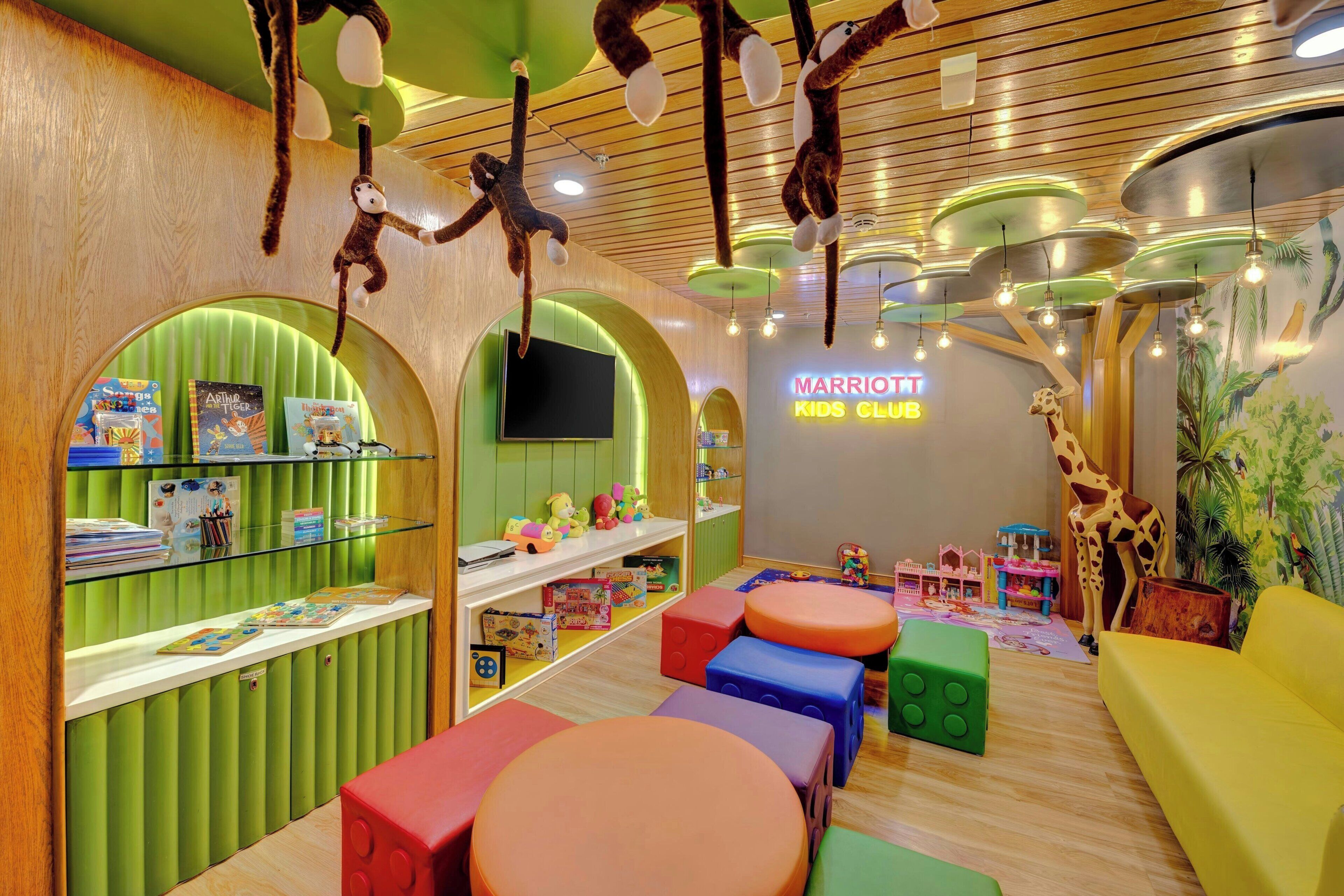 A children's play area with colorful seating, hanging toys, and a 'Marriott Kids Club' sign.