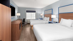 A hotel room with two beds, a desk, a chair, a TV, and a window.
