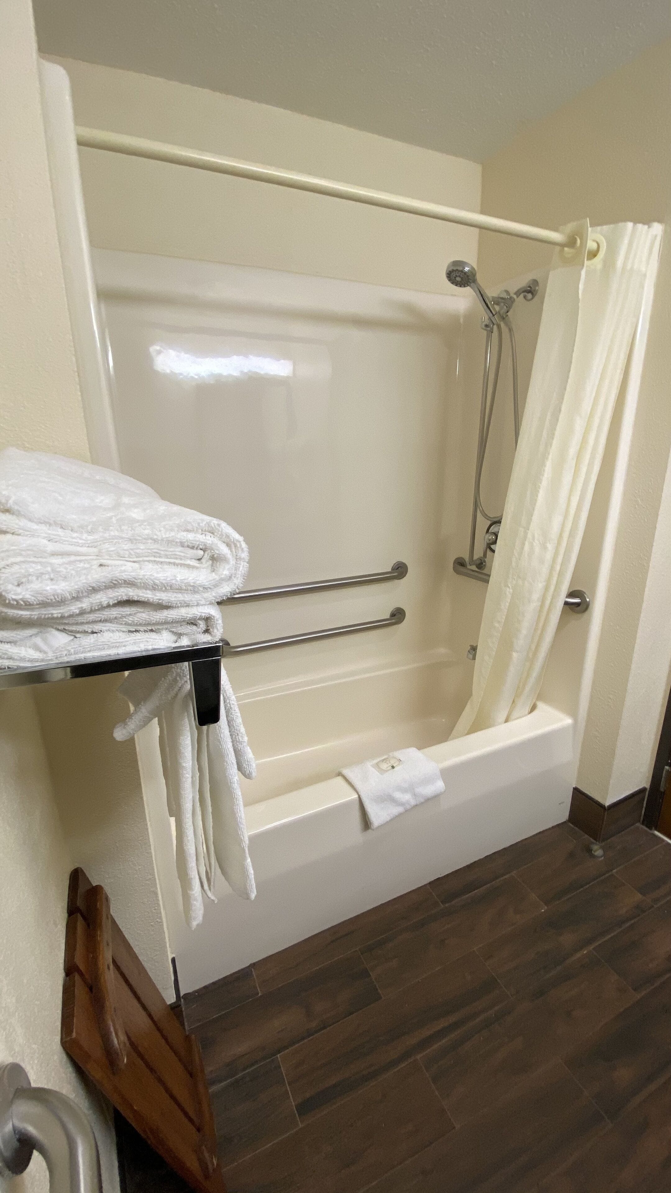 A bathroom with a bathtub, a shower, and a towel rack with folded towels.