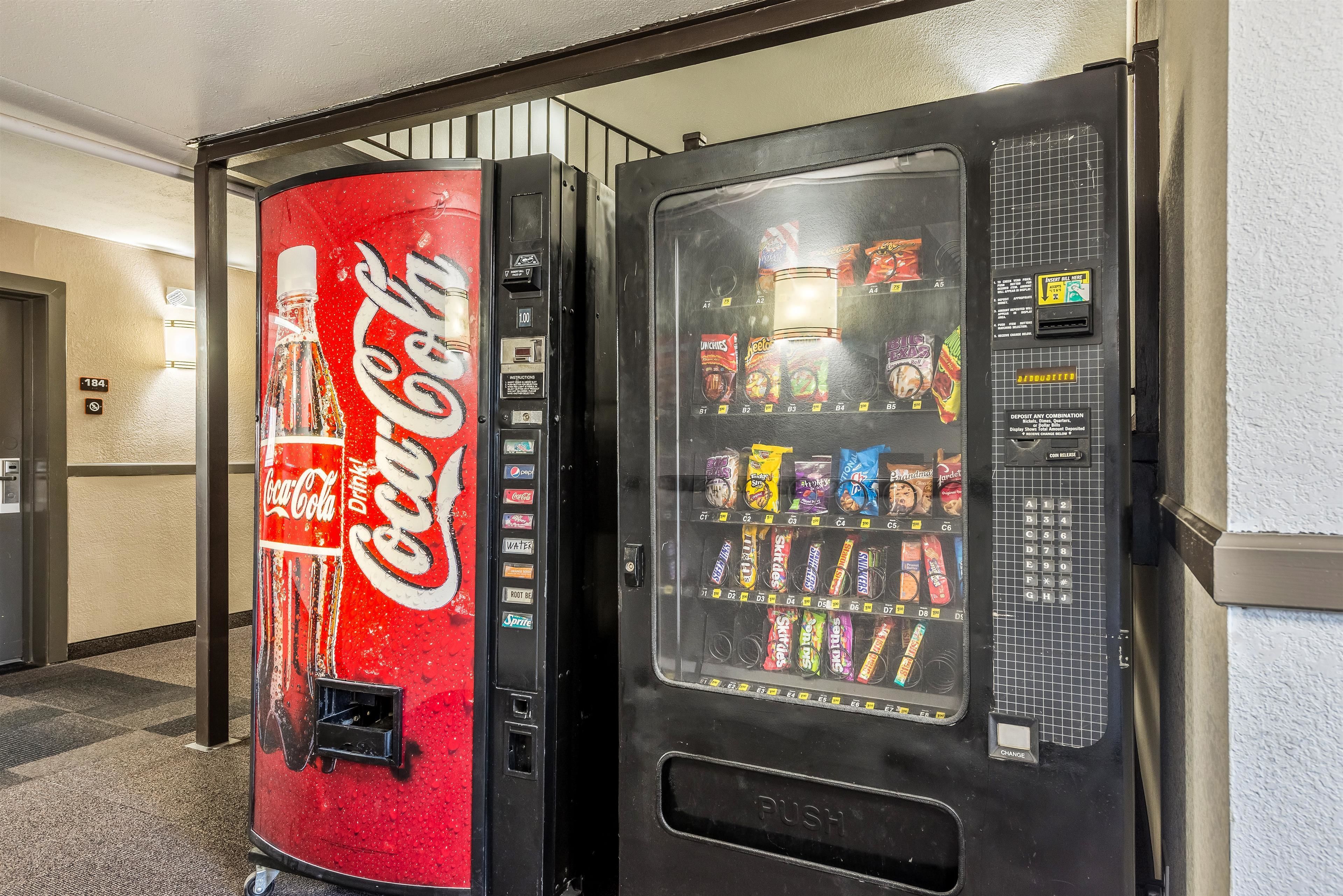 Máquina expendedora de Coca-Cola y máquina expendedora de aperitivos en un pasillo de hotel.