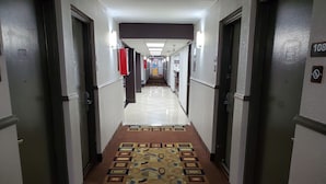 Un pasillo de hotel con alfombra estampada, puertas a ambos lados y suelo de baldosas.