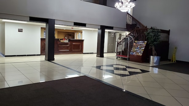 Un vestíbulo con piso a cuadros, un mostrador de recepción, una escalera y un candelabro.