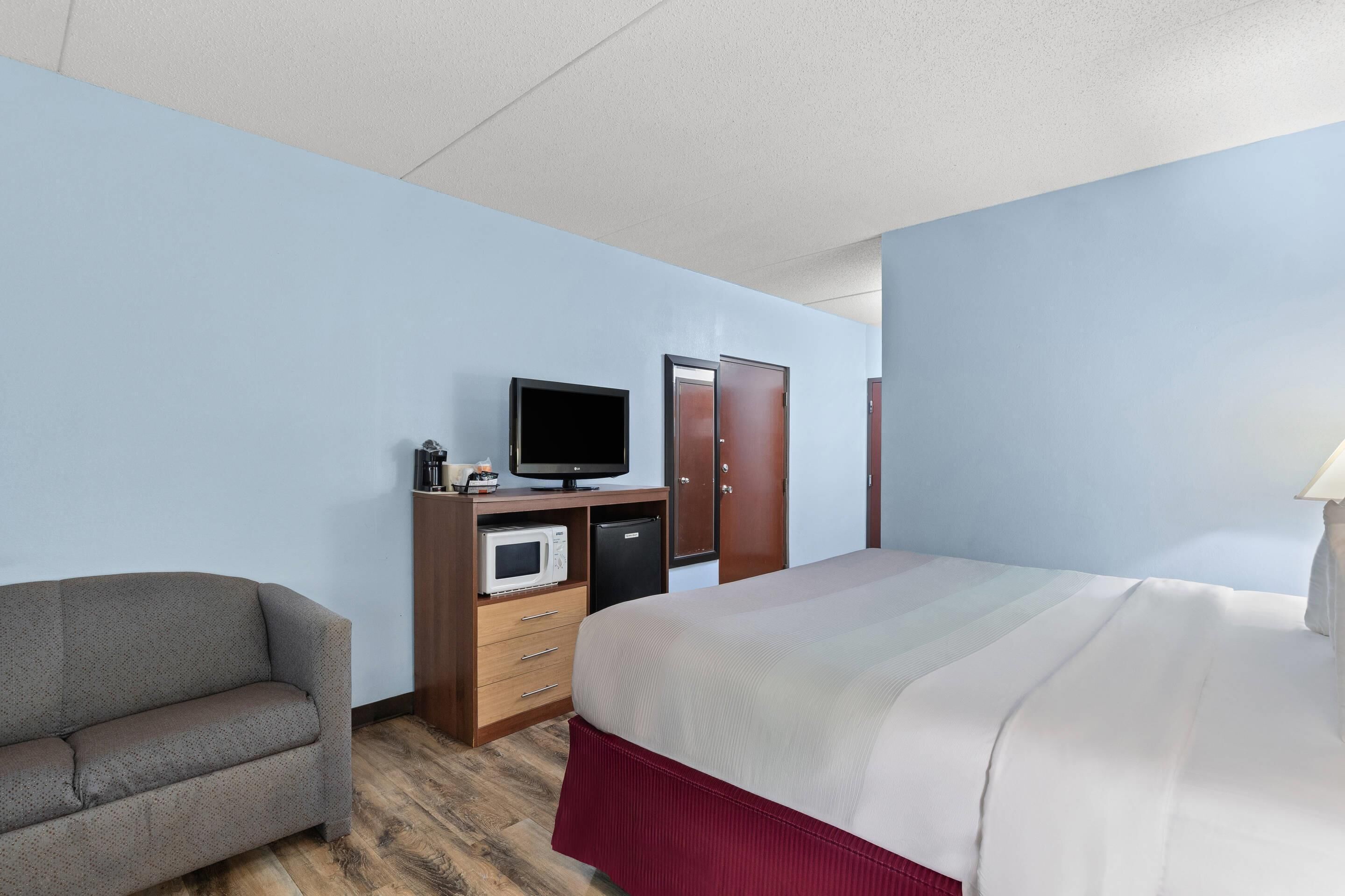 Une chambre d’hôtel équipée d’un lit, d’une télévision, d’un four à micro-ondes, d’un bureau et d’une chaise.