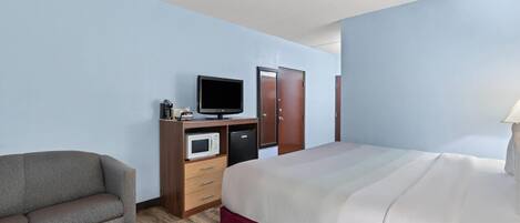 Une chambre d’hôtel équipée d’un lit, d’une télévision, d’un four à micro-ondes, d’un bureau et d’une chaise.