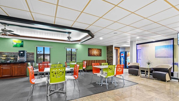 A modern dining area with green walls, multiple seating options, and a ceiling fan. - Quality Inn Hixson - Chattanooga (Hixson)