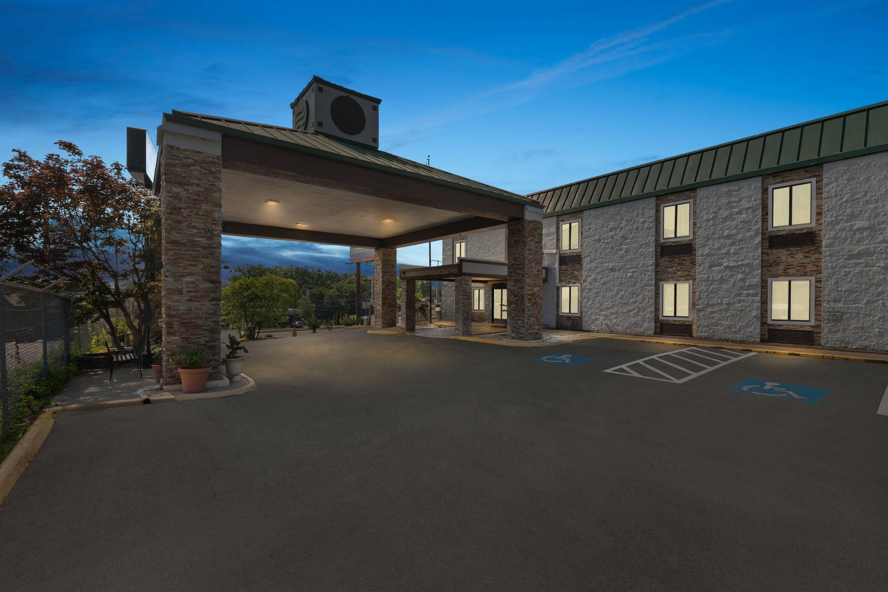 A building with a covered entrance, stone pillars, and a parking lot with handicapped parking spaces.