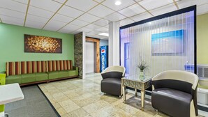 A lobby with a green wall, a seating area with a sofa, two armchairs, a small table, and a decorative wall with a Pepsi logo. - Quality Inn Hixson - Chattanooga (Hixson)