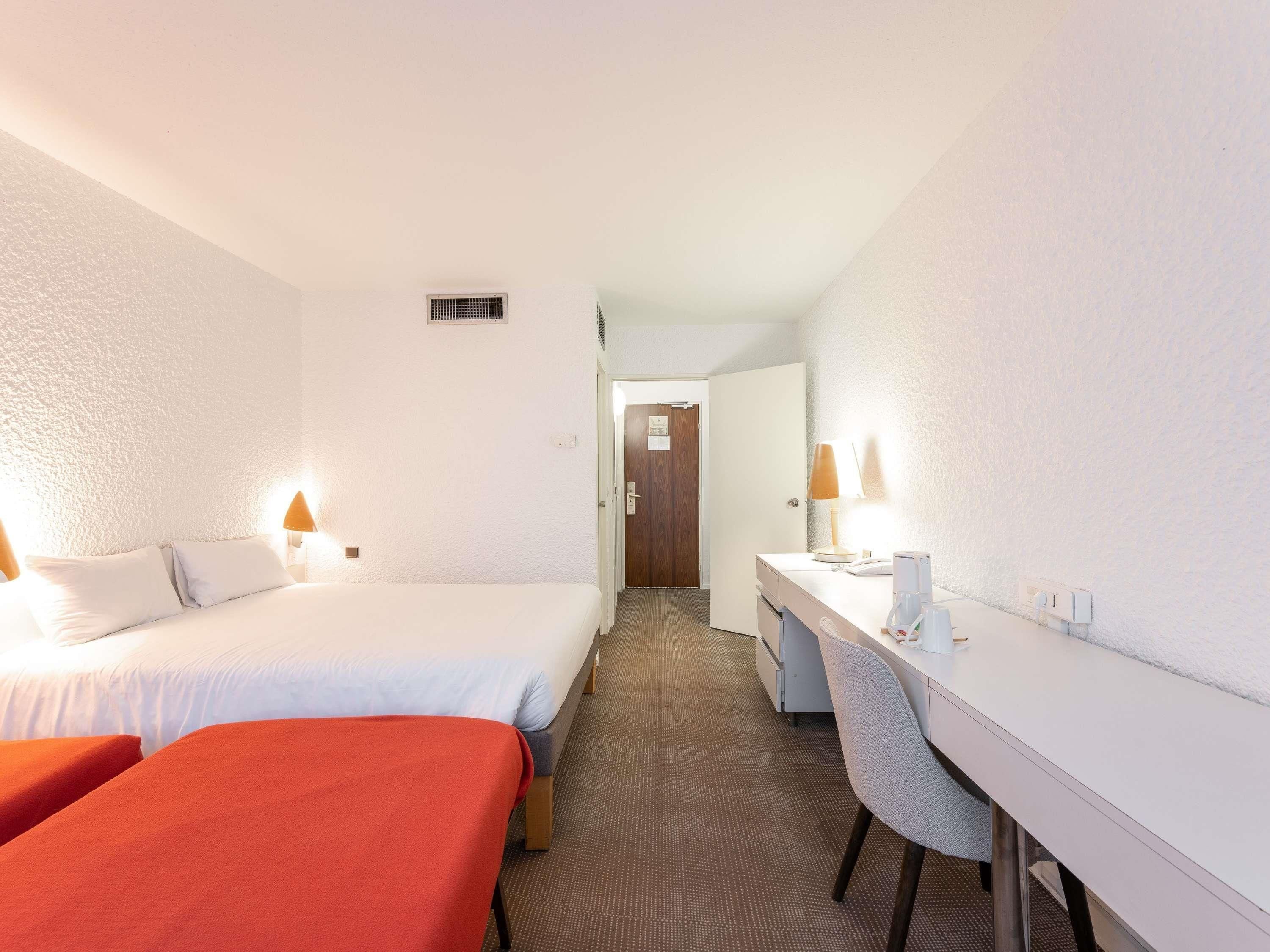 Una habitación de hotel con una cama, un escritorio y una silla.