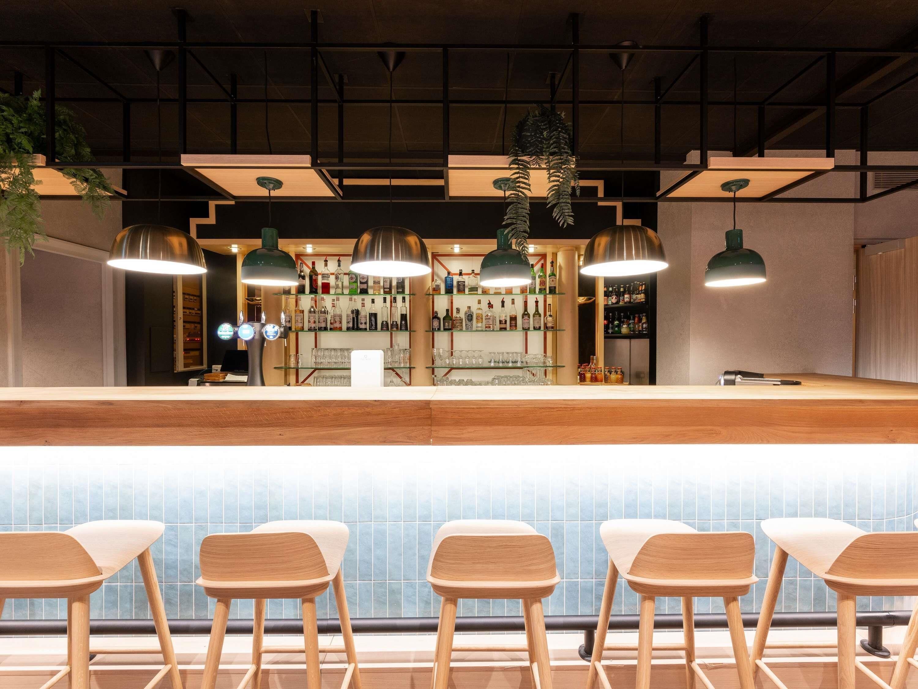 A bar area with wooden bar counter, hanging pendant lights, and bar stools.
