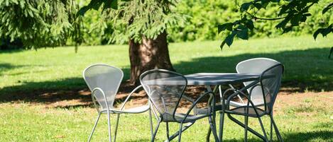 A metal table and chairs set outdoors with a tree in the background.