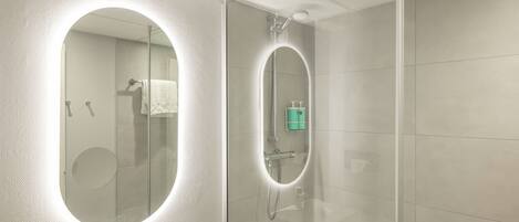 A modern bathroom with a large mirror, a sink, and a shower area.