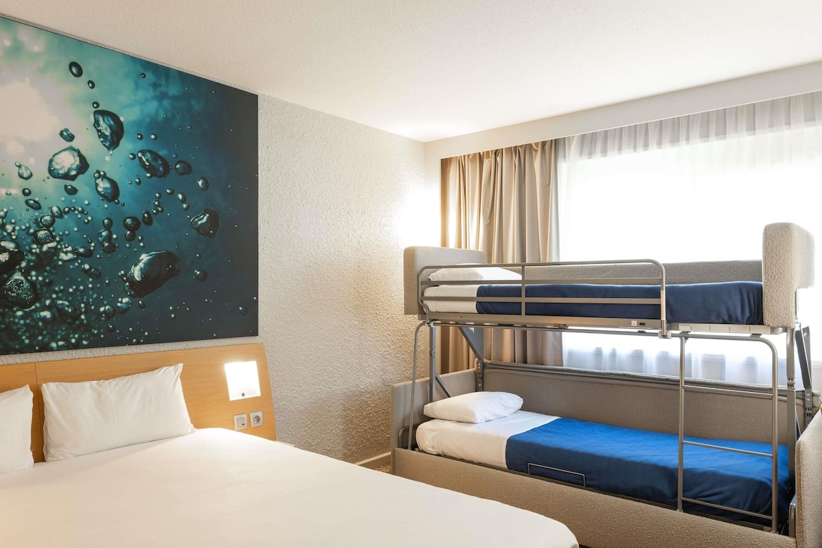 Ein Hotelzimmer mit Etagenbett, einem Doppelbett und einer Wandmalerei.