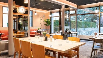 A restaurant interior with a large dining table, multiple chairs, and a seating area with a sofa.