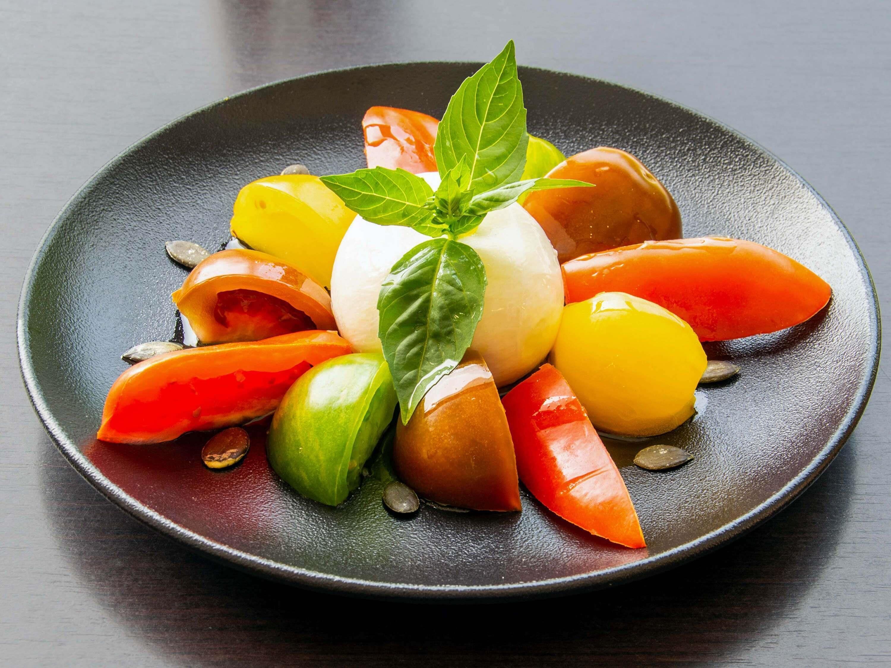 Une assiette de salade de fruits colorée, garnie d’une feuille de basilic.