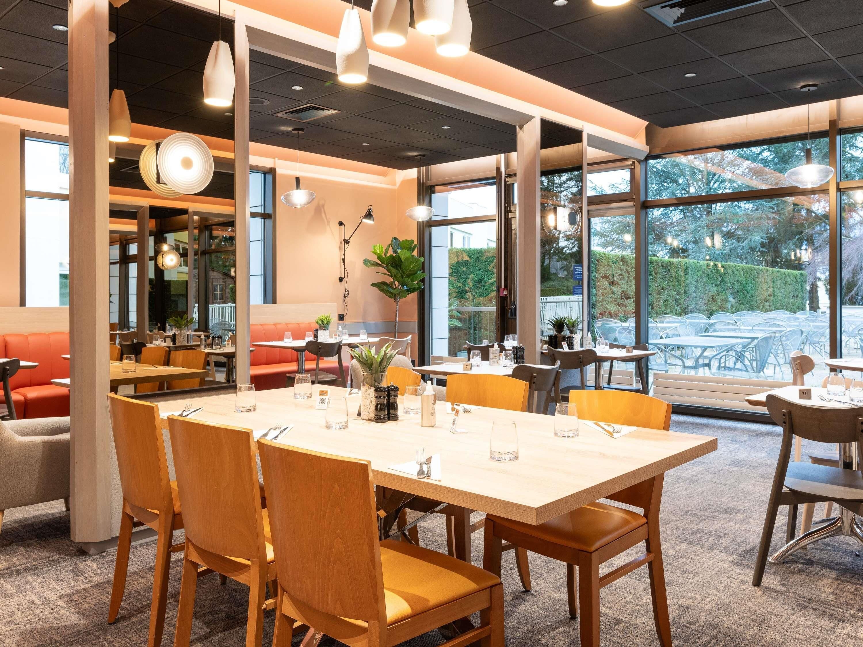 A restaurant interior with a large dining table, multiple chairs, and a seating area with a sofa.