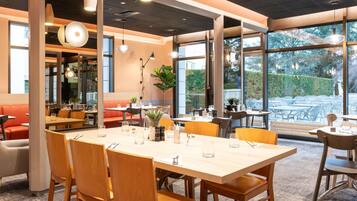 A restaurant interior with a large dining table, multiple chairs, and a seating area with a sofa.
