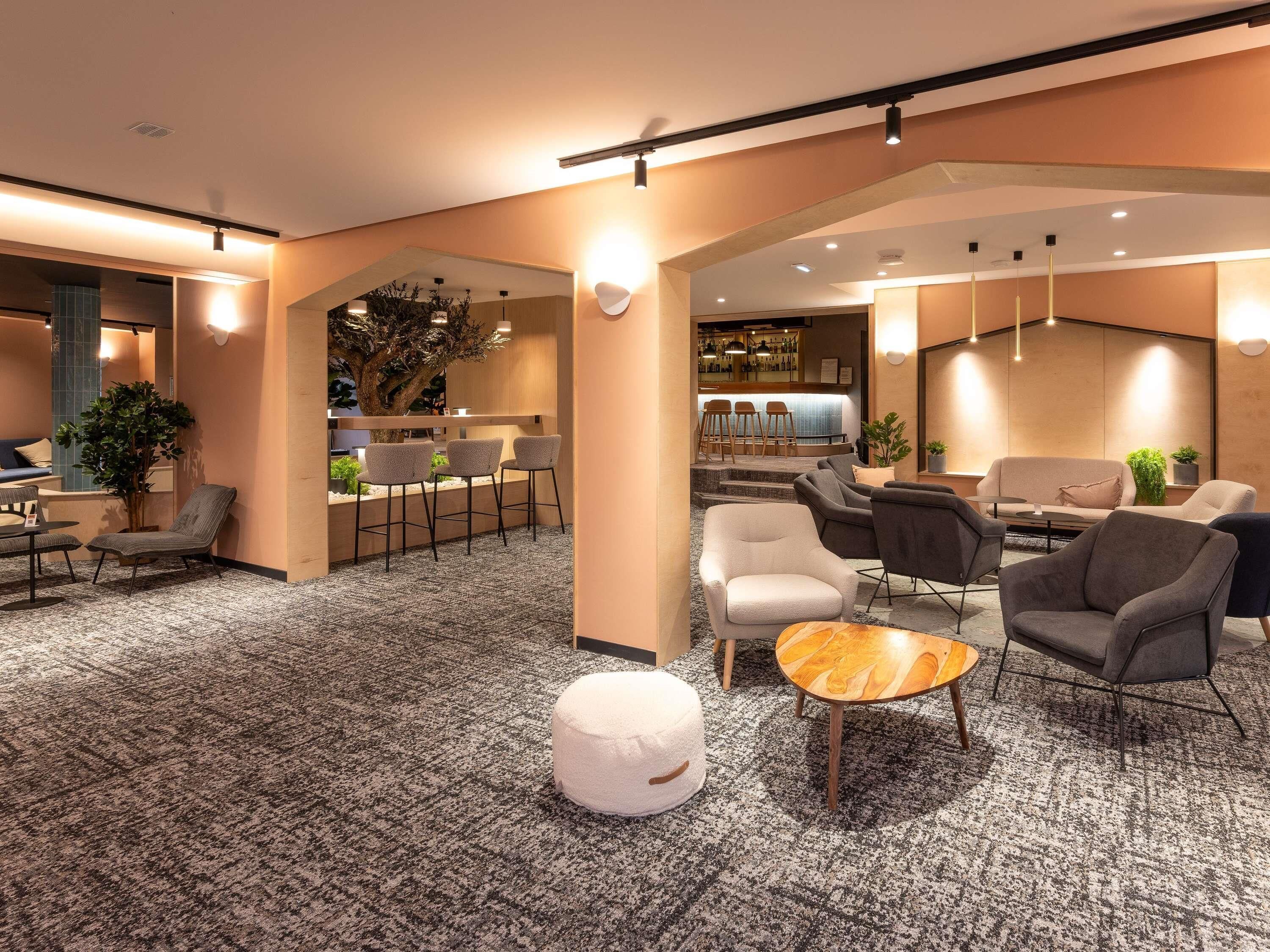 A spacious lobby with a bar area, seating arrangements, and a large tree.