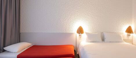 Habitación de hotel con dos camas, una cortina gris y una pared con textura.