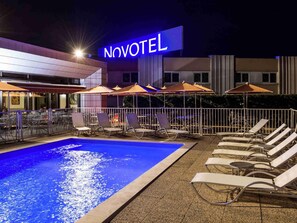 Una piscina al aire libre de temporada, sombrillas