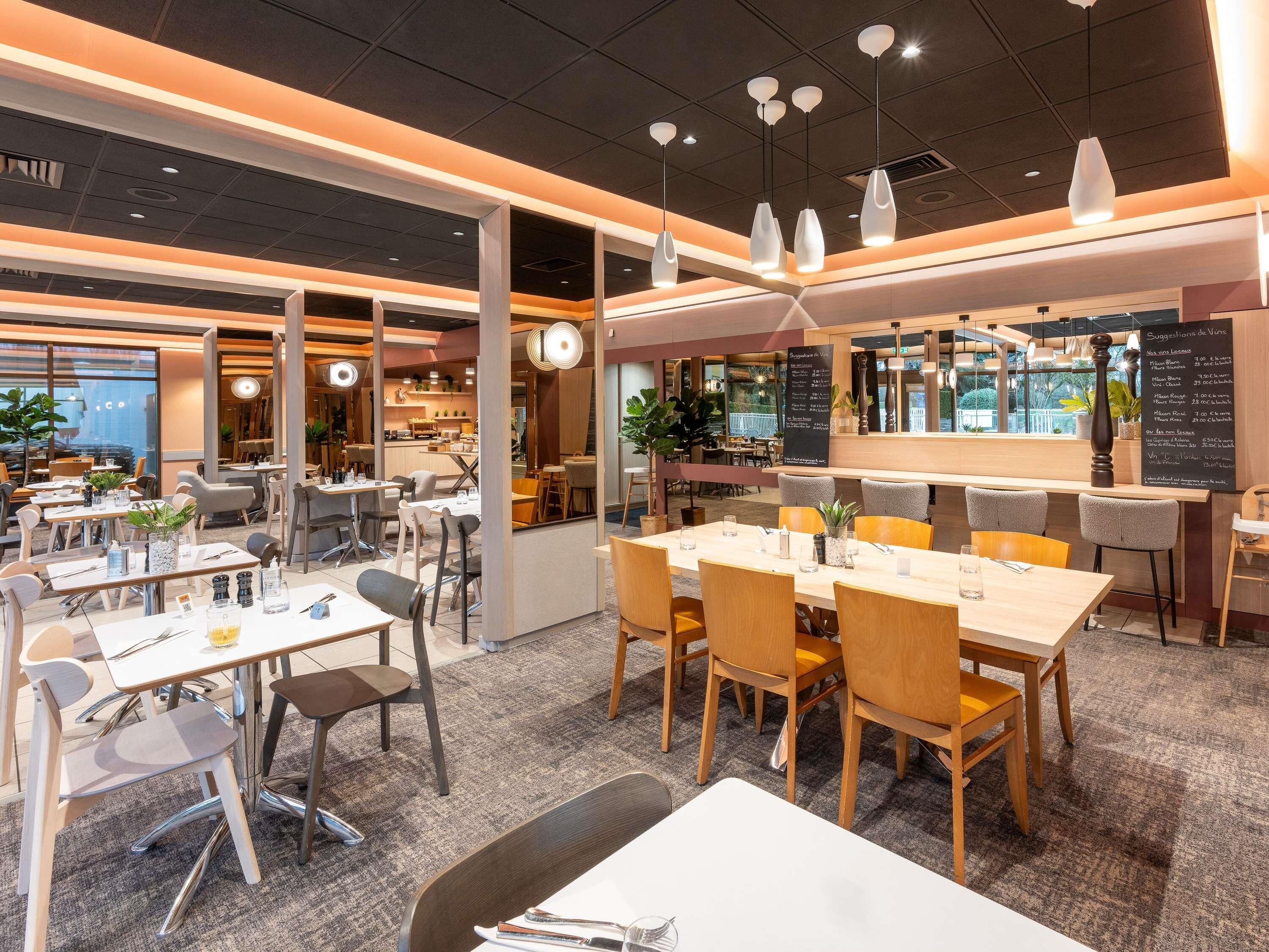 A modern restaurant interior with multiple dining areas, a bar, and a menu board.