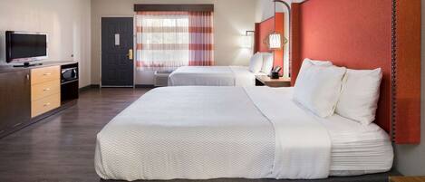 Una habitación de hotel con una cama grande, un televisor, un escritorio con lámpara y una ventana con cortinas.