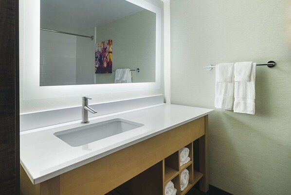 Un baño moderno con un espejo grande, un lavabo blanco y un perchero para toallas.