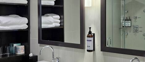 A modern bathroom with two sinks, a large mirror, and a glass shower enclosure.