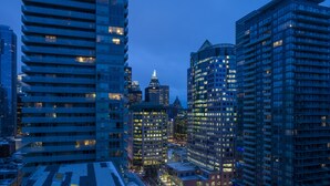 A cityscape at dusk with modern high-rise buildings, some with illuminated windows, and a clear sky.