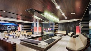 A modern lobby with a reception desk, seating area, and a water feature.