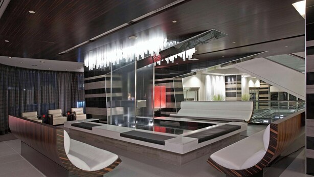 A modern lobby with a reception desk, seating area, and a staircase.