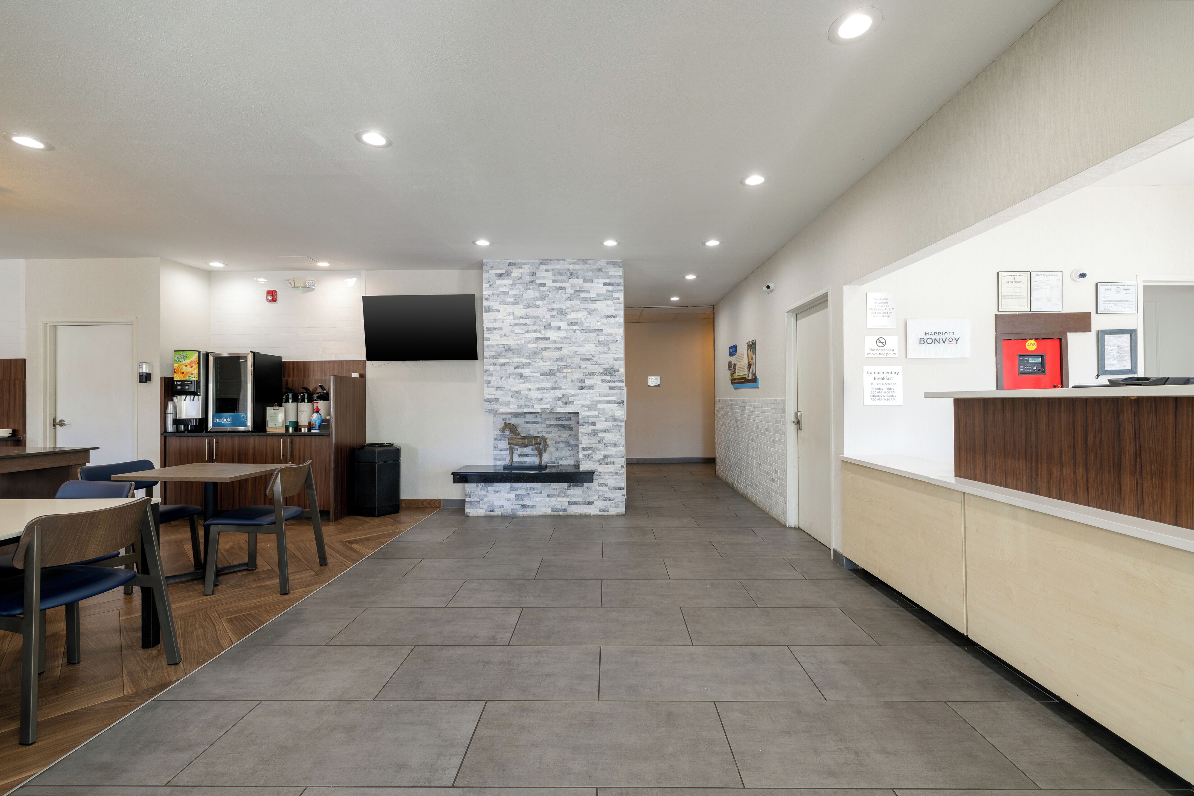 A modern hotel lobby with a reception desk, seating area, and a fireplace.