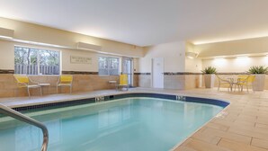An indoor swimming pool with tiled walls, yellow chairs, and a "No Lifeguard On Duty" sign.