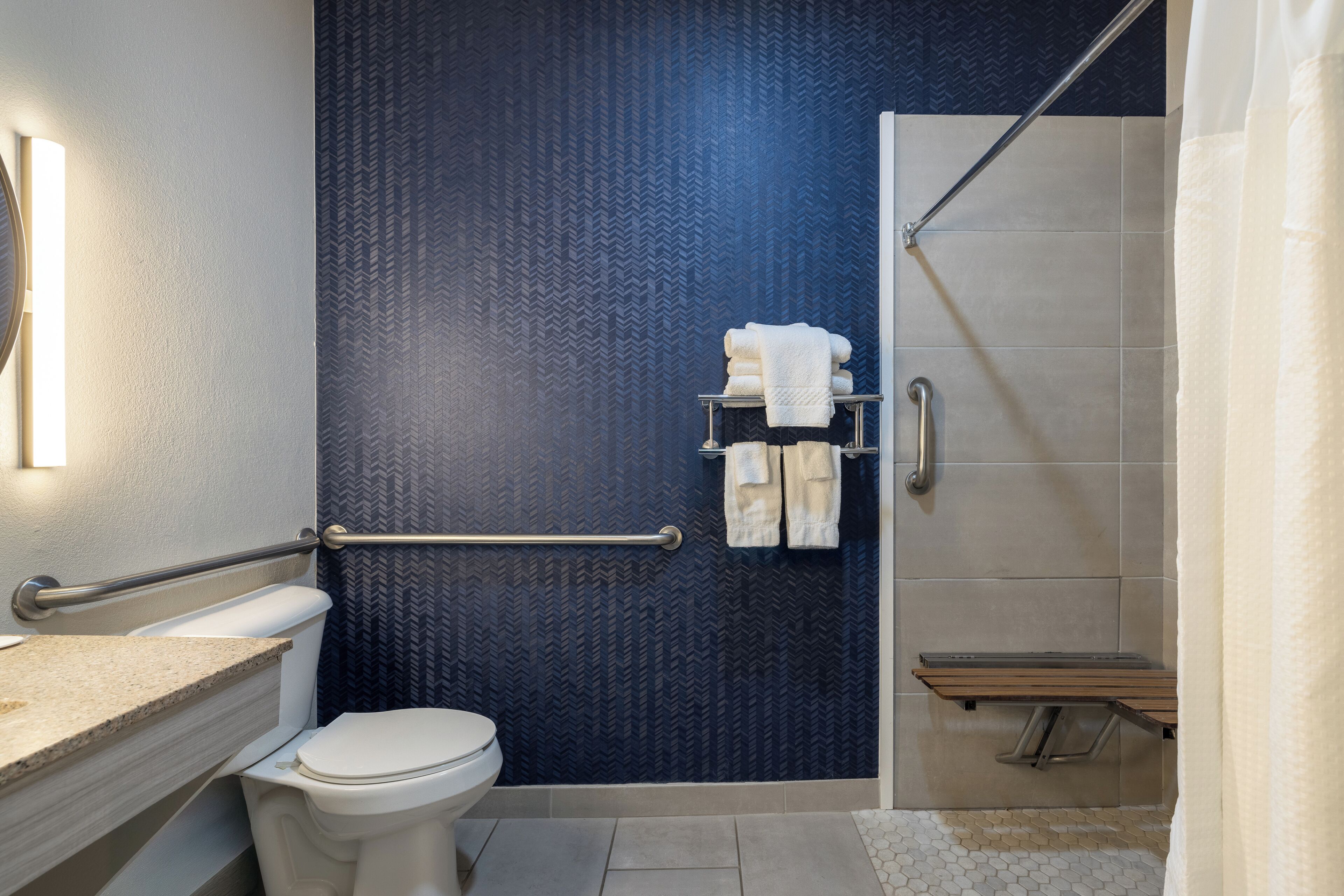 A modern bathroom with a toilet, a towel rack, a shower area, and a vanity with a mirror.