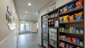 A corridor with a snack vending machine and a refrigerator.