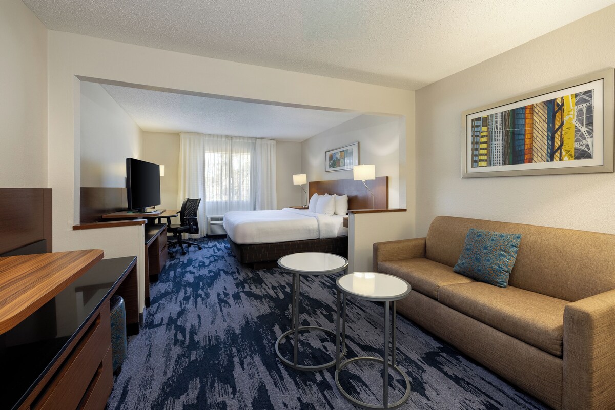 Una habitación de hotel con cama, sofá, escritorio, silla y televisor.