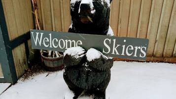 Ein mit Schnee bedeckter Bär hält ein Schild, auf dem „Willkommen Skifahrer“ steht.