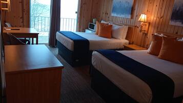 A room with two beds, a desk, and a chair. There is a window with curtains, a painting on the wall, and a lamp on the desk.