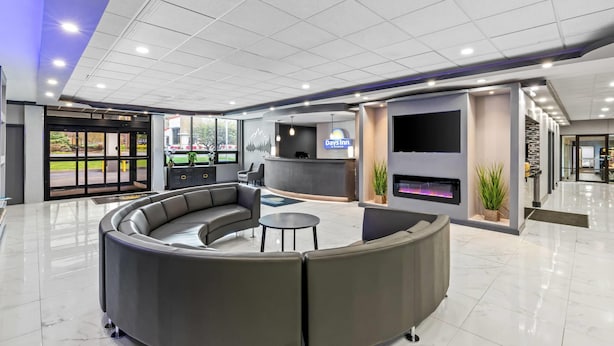 Um lobby moderno com um sofá curvo, uma mesa de recepção e uma televisão de tela plana.
