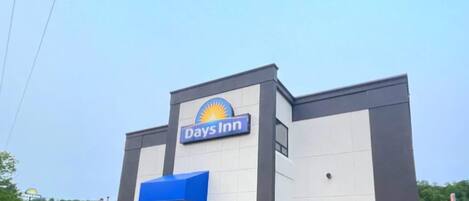A Days Inn building with a blue awning and a clear sky.