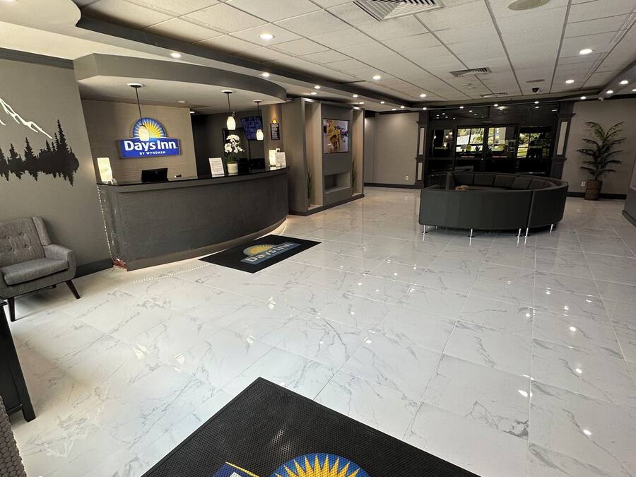 A clean, modern hotel lobby with a reception desk, seating area, and a large plant.