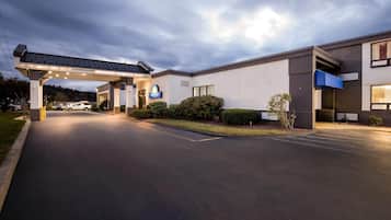 Entrada de hotel con un camino cubierto, un letrero de McDonald's y un estacionamiento.