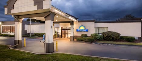 Entrada de um hotel Days Inn, com galeria coberta, área de estacionamento e paisagismo bem cuidado.
