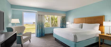 A hotel room with a bed, a desk, a chair, and a window with curtains.