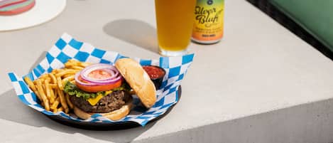 A meal consisting of a burger, fries, and a drink on a table outdoors.