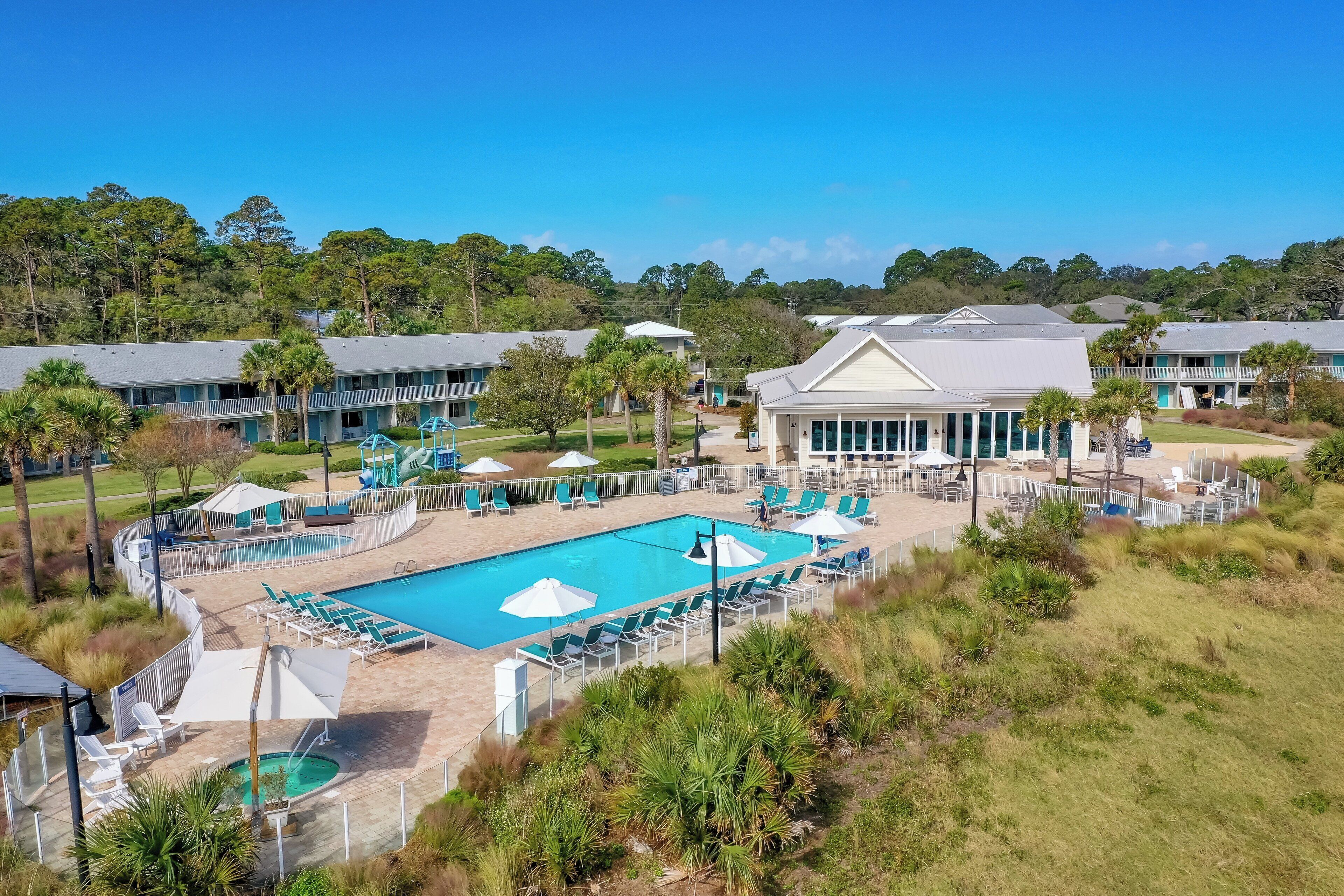 A resort with a large pool, lounge chairs, and a building with a balcony.