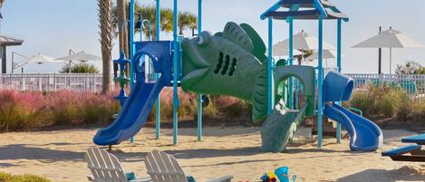A beachside playground with slides and a seating area.