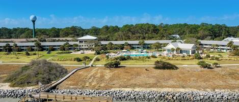 A coastal hotel with a rocky shoreline, a wooden pier, and a large building complex with multiple structures.