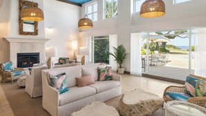 A spacious living area with a fireplace, comfortable seating, and large windows offering a view of the outdoors. - Holiday Inn Resort Jekyll Island by IHG (Jekyll Island)