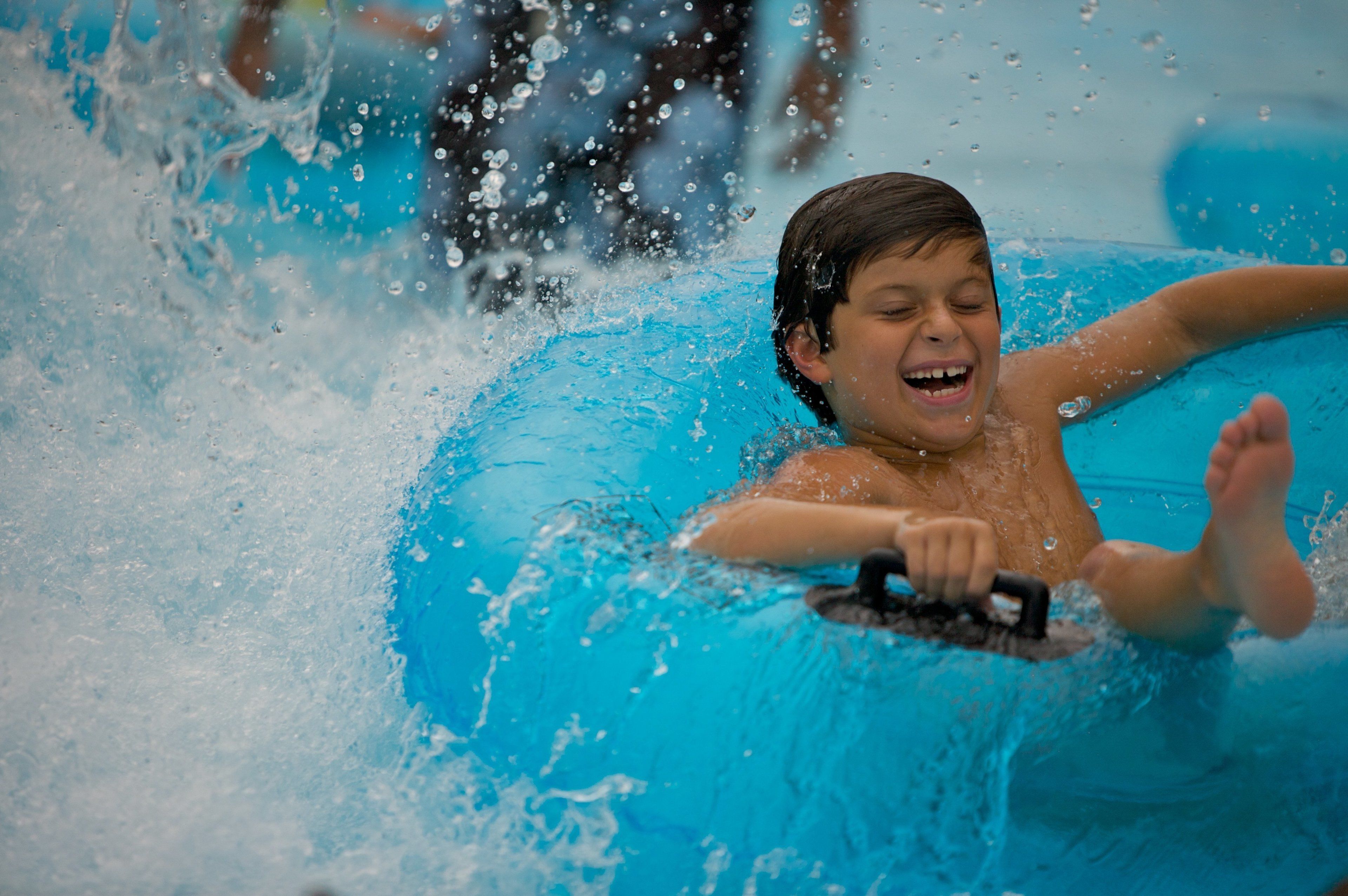 A child in a blue inflatable pool with water splashing around.